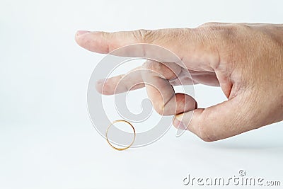 Divorce concept. Male hand kicking wedding ring on white background. Relationship breakup. Unfaithful spouse. Person pulls off the Stock Photo