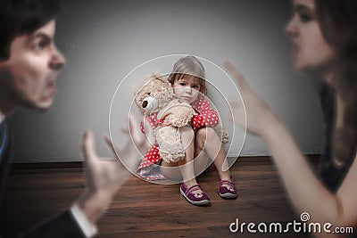 Divorce concept. Sad child is sitting at floor when parents argue. Stock Photo