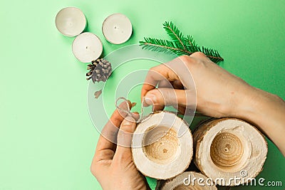 DIY Christmas candle holder made of pine logs, candles, craft rope, fir branches and cones. Hands fasten and tie the rope. Step-by Stock Photo