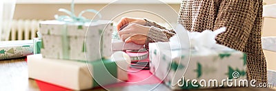 DIY Gift Wrapping Banner. Unrecognisable woman wrapping beautiful nordic style christmas gifts. Hands close up. Stock Photo