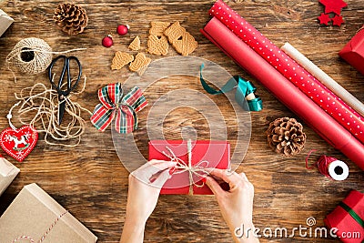 DIY Gift Wrapping. Woman wrapping beautiful red christmas gifts on rustic wooden table. Overhead point of view. Stock Photo