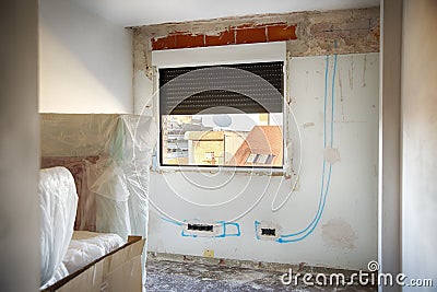 DIY, house indoor improvements in a messy room construction. Renovated windows, blue lines to electrical installation and wall Stock Photo