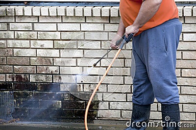 Man powerwashing mold of wall - DIY Stock Photo