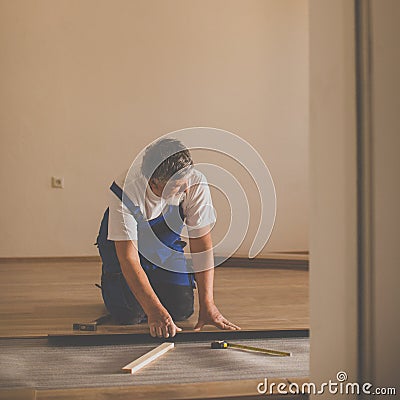 Senior landlord lying parquet floor board/laminate flooring in a rental appartement Stock Photo