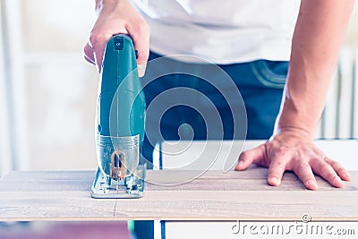 DIY worker cutting wooden panel with jig saw Stock Photo