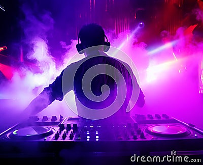 dj in concert in a flood of laser and strobe lights and in a light smoky haze, a magical club atmosphere full of colors Stock Photo