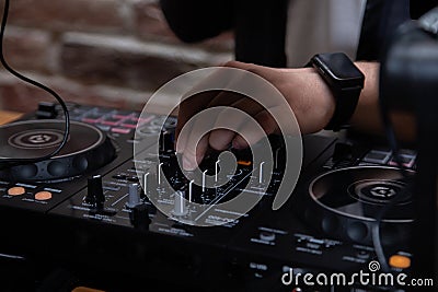 A DJ in a nightclub at the control panel adjusts the music. Music is playing, creating an atmosphere. Stock Photo