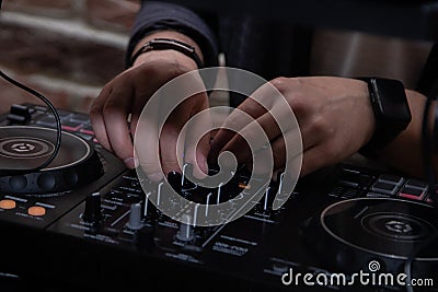 A DJ in a nightclub at the control panel adjusts the music. Music is playing, creating an atmosphere. Stock Photo