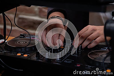 A DJ in a nightclub at the control panel adjusts the music. Music is playing, creating an atmosphere. Stock Photo