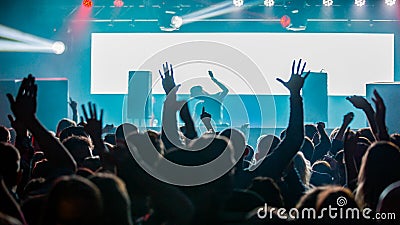 DJ performing for a crowd of party people with their hands in the air Editorial Stock Photo