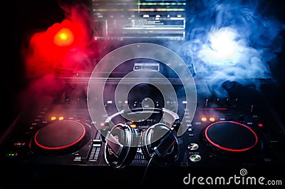 DJ Spinning, Mixing, and Scratching in a Night Club, Hands of dj tweak various track controls on dj's deck, strobe lights and fog, Stock Photo