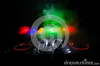 DJ Spinning, Mixing, and Scratching in a Night Club, Hands of dj tweak various track controls on dj's deck, strobe lights and fog, Stock Photo