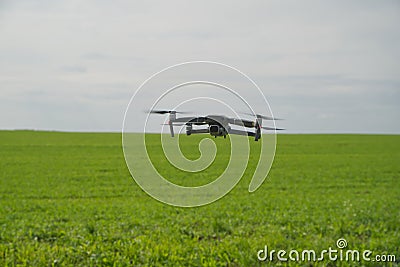 DJI drone hovers over a green field, light sky Editorial Stock Photo