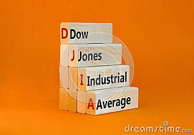 DJIA Dow Jones industrial average symbol. Concept words DJIA Dow Jones industrial average on wooden block on beautiful orange Stock Photo