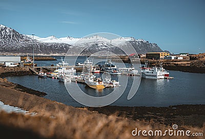 Djupivogur fishing village full of colorful boats in Iceland. Winter scenery with snow capped mountains. Editorial Stock Photo