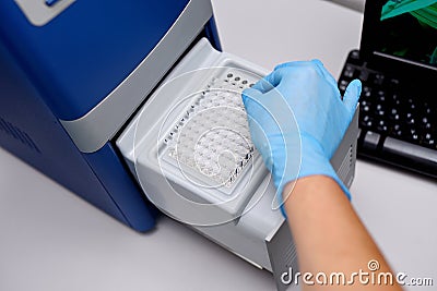 Dna test in the lab. the technician inserts the test tubes into the dna analyzer. Gloved hands close up Stock Photo