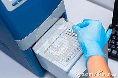 Dna test in the lab. the technician inserts the test tubes into the dna analyzer. Gloved hands close up Stock Photo