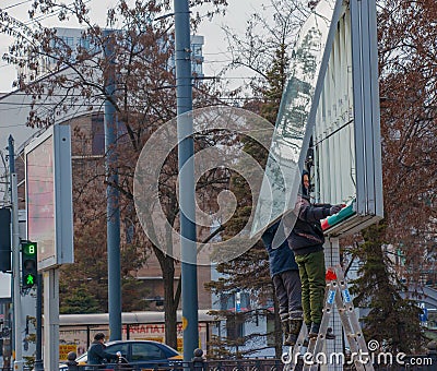 Installation of outdoor advertising in the city. Specialists climb the stairs to the billboard. Work at height Editorial Stock Photo