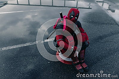 DNIPRO, UKRAINE - MARCH 28, 2019: Deadpool cosplayer posing sitting with weapon Editorial Stock Photo