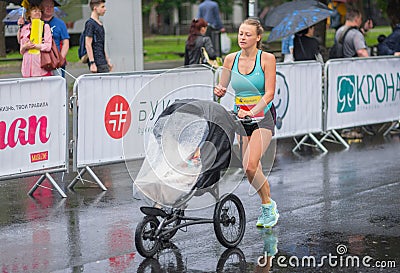 Young woman running with baby carriage during of the `Interipe Dnipro Half Marathon` race Editorial Stock Photo