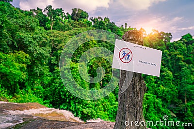 Do not walk of the trail. Warning sign in national park hang on concrete pole at waterfall in green tropical forest. Warning sign Stock Photo