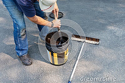 Driveway maintenance, stirring sealant before pouring Stock Photo