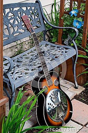 Dobro Style Guitar Leaning against Metal Bench Stock Photo