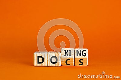 Docs or doxing symbol. Concept words Docs Doxing on wooden block. Beautiful orange table orange background. Business docs or Stock Photo