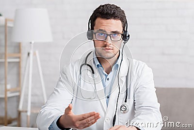 Doctor advice or online webinar. Serious doctor in glasses and headphones explains something Stock Photo