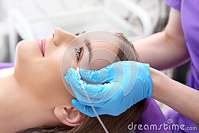 The doctor of aesthetic medicine performs a facial skin scraping treatment with a syringe. Stock Photo