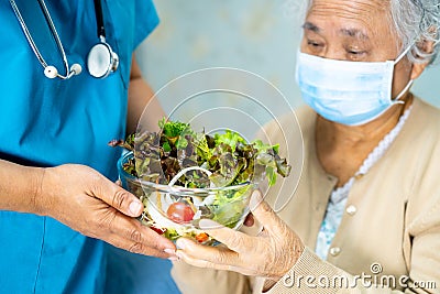 Doctor and Asian senior or elderly old lady woman patient holding breakfast vegetable healthy food with hope and happy while Stock Photo