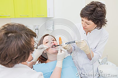 Doctor and assistant making Caries treatment to Patient at a dentist office Stock Photo