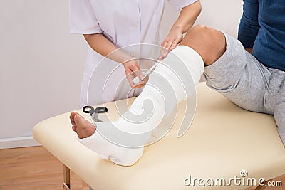 Doctor bandaging patient's leg Stock Photo