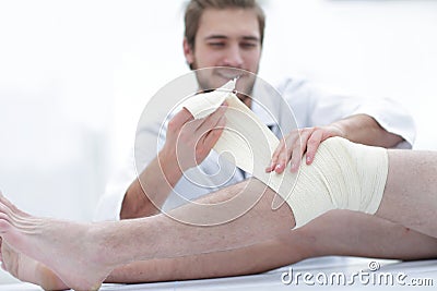 Doctor bandaging a wound on the leg of the patient Stock Photo