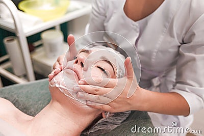 Doctor beautician makes cosmetic facial massage. Woman relaxes on a cosmetic chair Stock Photo