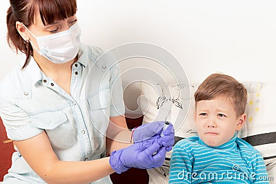 doctor in blue medical gloves injects a sick child with a syringe Stock Photo