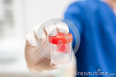 Drug test. Doctor in blue uniform and medical gloves holding a container for semen analysis. Donor sperm for artificial Stock Photo