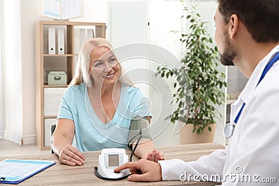 Doctor checking mature woman`s pulse with medical device Stock Photo