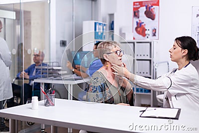 Doctor checking sore throat of elderly woman Stock Photo