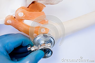 Doctor checks with stethoscope sprain or tear ligaments and cartilage of joint presence of fractures, osteopathy, osteoarthritis, Stock Photo