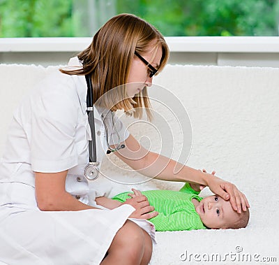 Doctor checks the temperature of baby touching his forehead Stock Photo