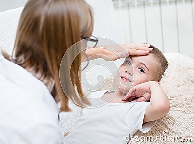 Doctor checks the temperature of a boy touching his forehead Stock Photo