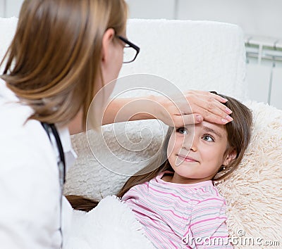 The doctor checks the temperature of a smiling girl Stock Photo