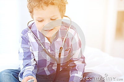 Doctor and child patient. Little boy play with stethoscope while physician communicate with him. hildren`s therapy and Stock Photo