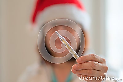 Doctor in christmas hat holding thermometer in hand. Stock Photo