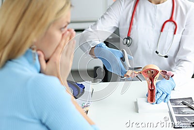 Doctor climbing fallopian tube with scissors onto artificial models on uterus and ovaries in clinic Stock Photo