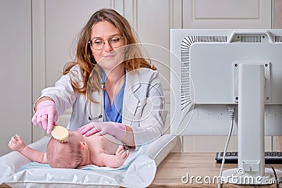 The doctor is combing the hair of a newborn baby. Nurse in uniform with a comb in hand for a child Stock Photo