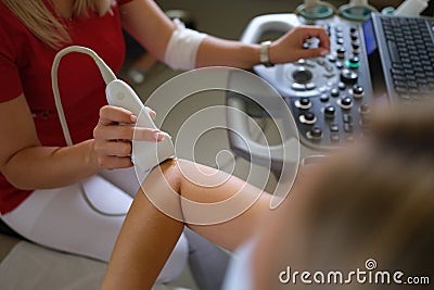 Doctor conducting ultrasound examination of elbow joint of patient hand in clinic closeup Stock Photo