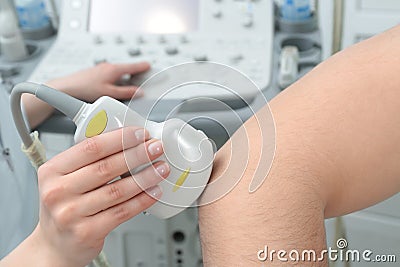 Doctor conducting ultrasound examination of patient`s elbow in clinic Stock Photo
