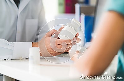 Doctor consulting patient about right medication. Physician holding medicine and pills in hand. Stock Photo